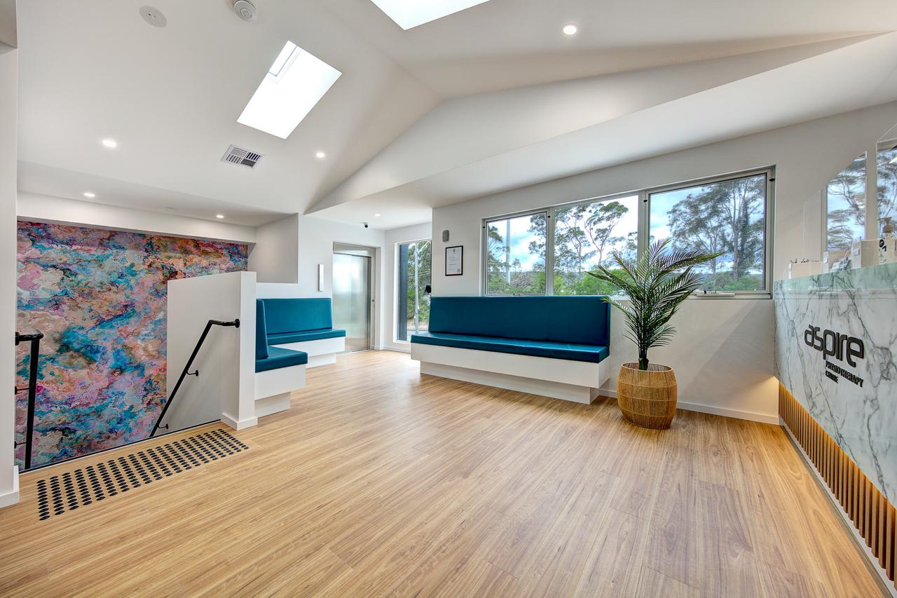 Inside Aspire Physiotherapy Centre, light-filled waiting room with timber floors and feature artwork